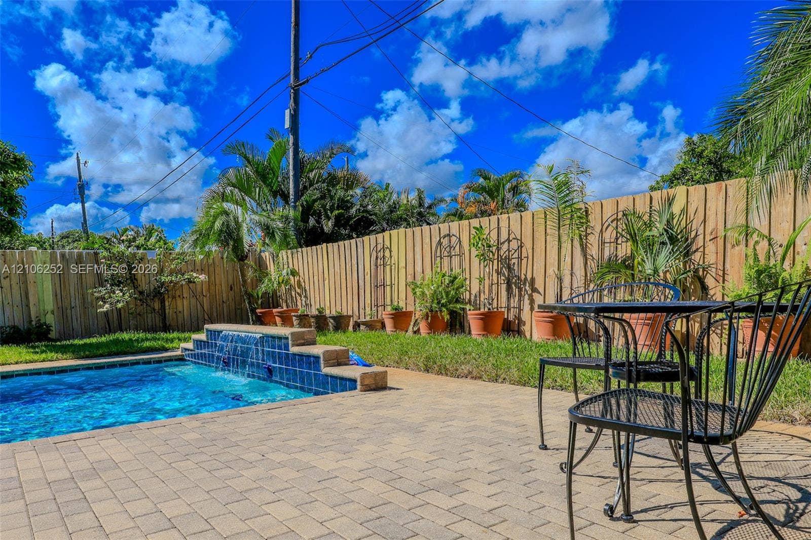 225 E Ilex Drive, Lake Park, Lake Park, FL 33403 Backyard featuring a paver patio, a swimming pool with a tiled water feature, and a privacy fence