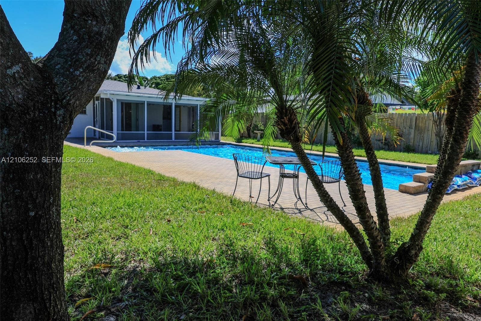 225 E Ilex Drive, Lake Park, Lake Park, FL 33403 Rectangular swimming pool with paver decking, screened-in porch, and perimeter fencing
