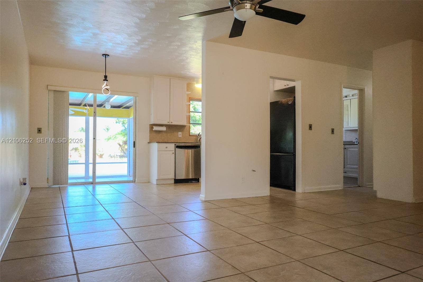 225 E Ilex Drive, Lake Park, Lake Park, FL 33403 Large-format tile flooring, white kitchen cabinetry, stainless steel dishwasher, glass sliding patio doors, and a ceiling fan with integrated lighting