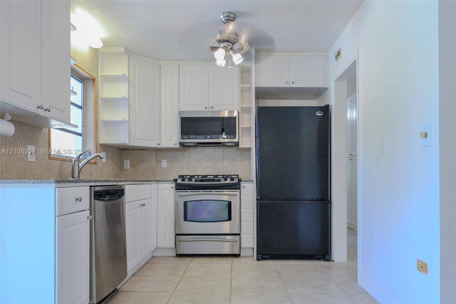 225 E Ilex Drive, Lake Park, Lake Park, FL 33403 Kitchen featuring white cabinetry with open shelving, stone-finish countertops, tile flooring, and stainless steel appliances