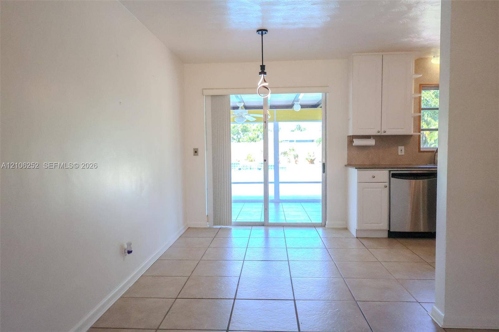 225 E Ilex Drive, Lake Park, Lake Park, FL 33403 Ceramic tile flooring, white cabinetry, stainless steel dishwasher, and sliding glass doors with overhead pendant lighting