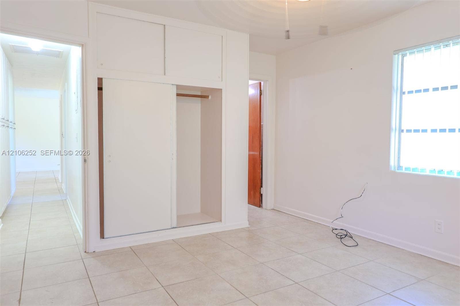 225 E Ilex Drive, Lake Park, Lake Park, FL 33403 Neutral-toned ceramic tile flooring, built-in floor-to-ceiling sliding closet cabinetry, and a window with horizontal blinds