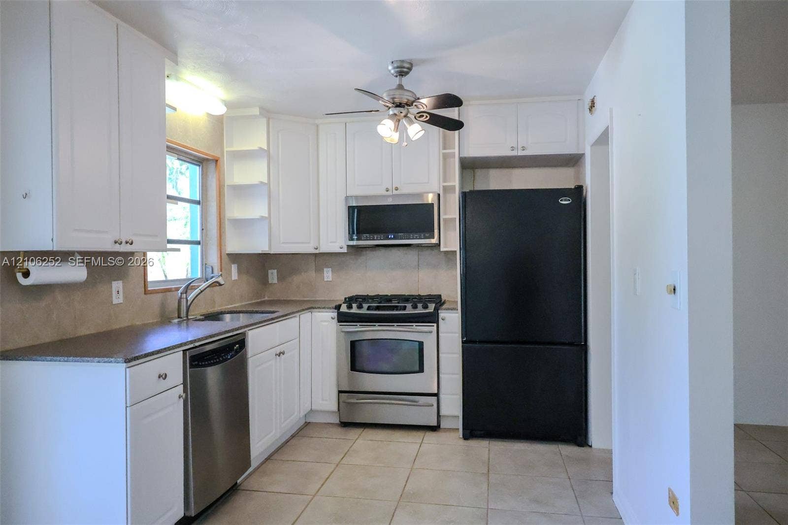 225 E Ilex Drive, Lake Park, Lake Park, FL 33403 Kitchen featuring white shaker-style cabinetry, neutral stone-finish countertops, tile flooring, and integrated stainless steel and black appliances