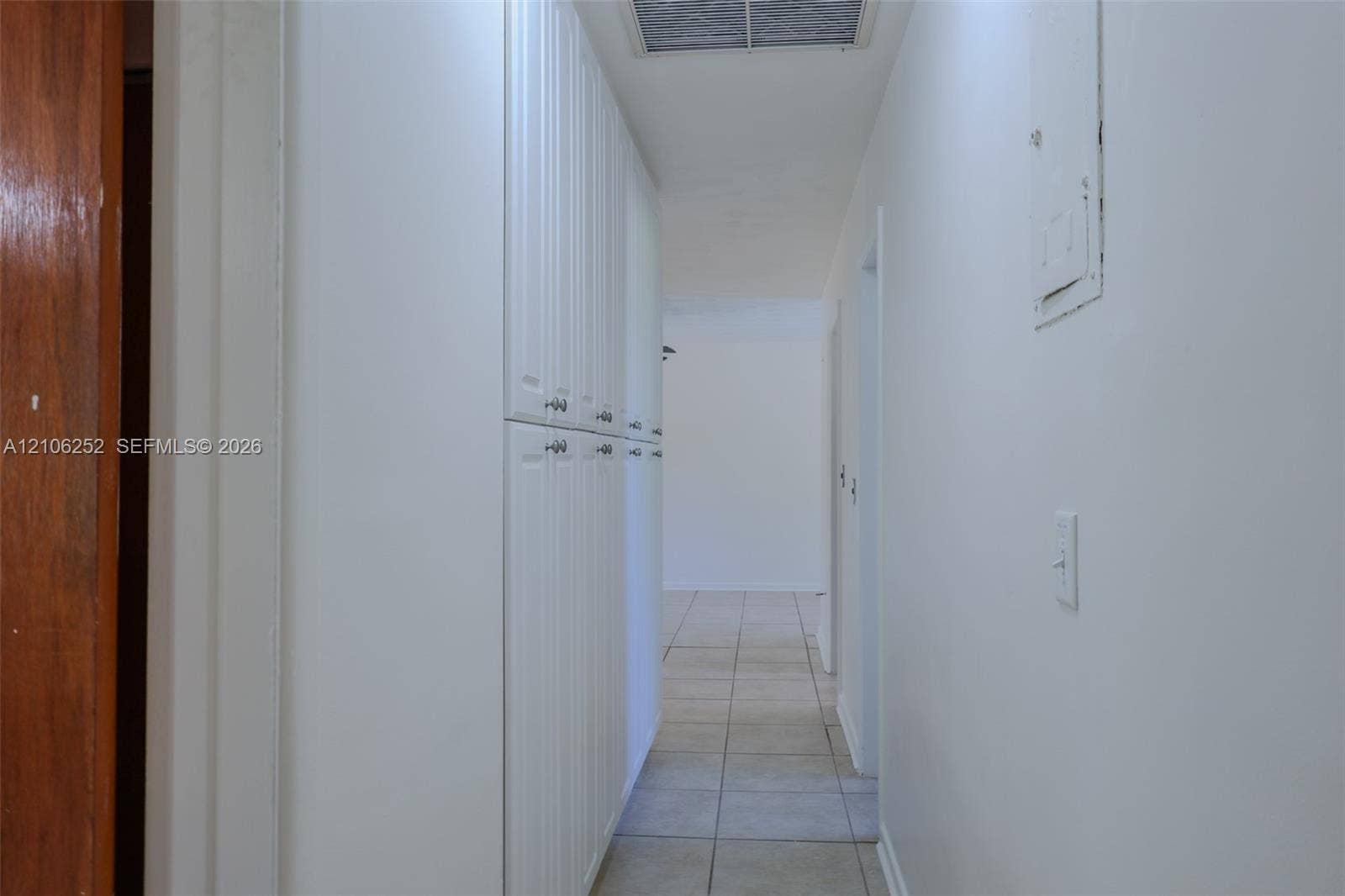 225 E Ilex Drive, Lake Park, Lake Park, FL 33403 Hallway featuring full-height white cabinetry with nickel hardware, neutral tile flooring, and a ceiling-mounted skylight