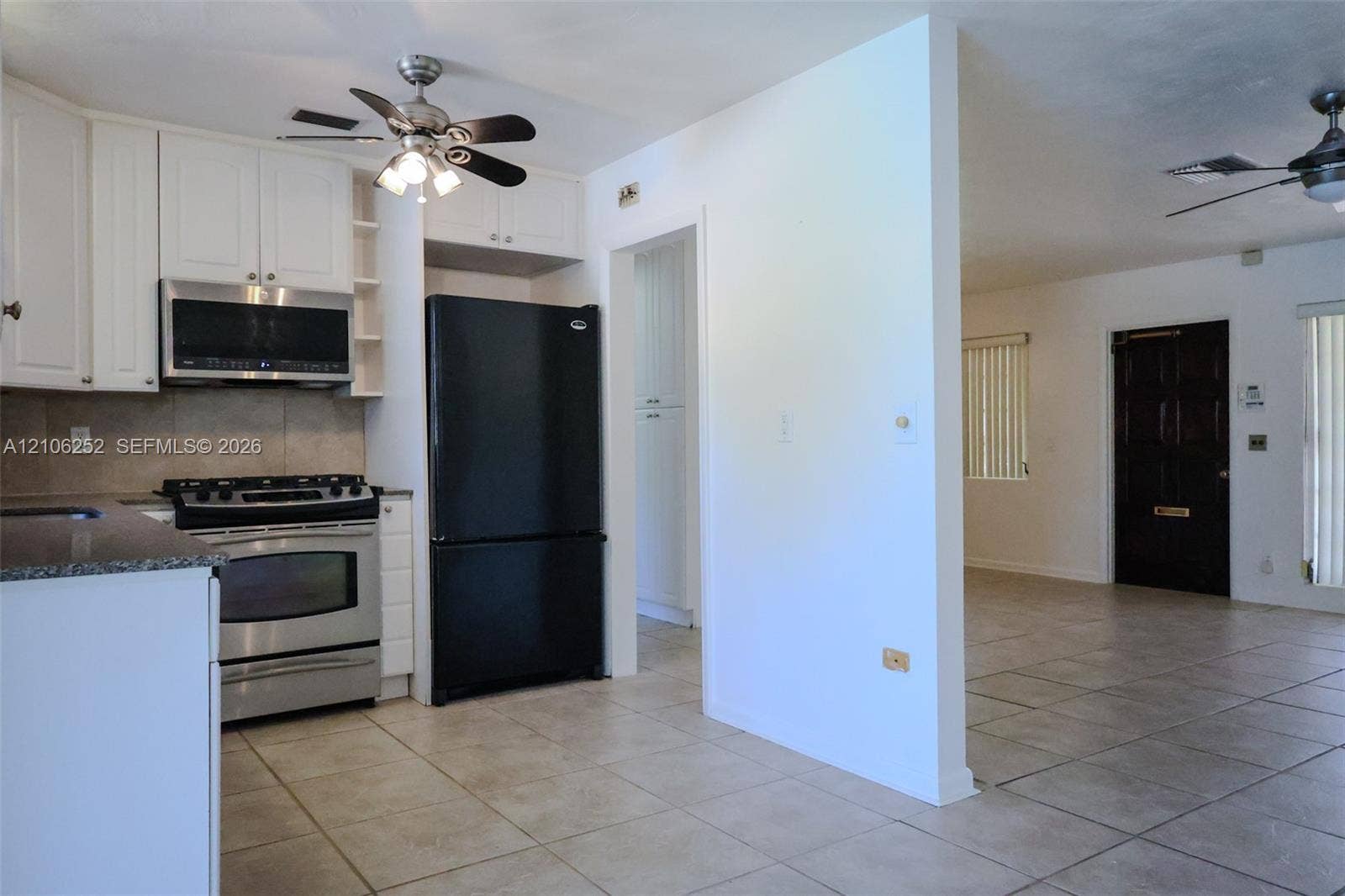 225 E Ilex Drive, Lake Park, Lake Park, FL 33403 Kitchen featuring white cabinetry, stone-finish countertops, stainless steel gas range, built-in microwave, and tile flooring throughout