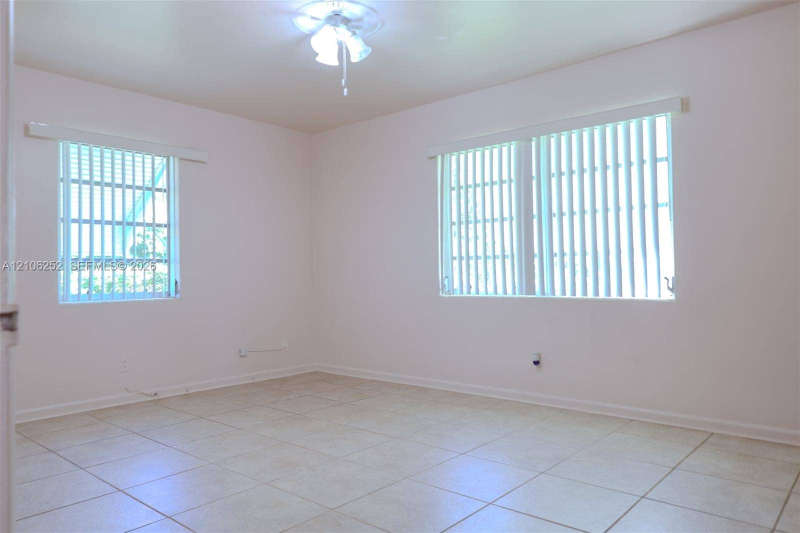 225 E Ilex Drive, Lake Park, Lake Park, FL 33403 Neutral-toned tile flooring, dual windows with vertical blinds, and a ceiling-mounted light fixture