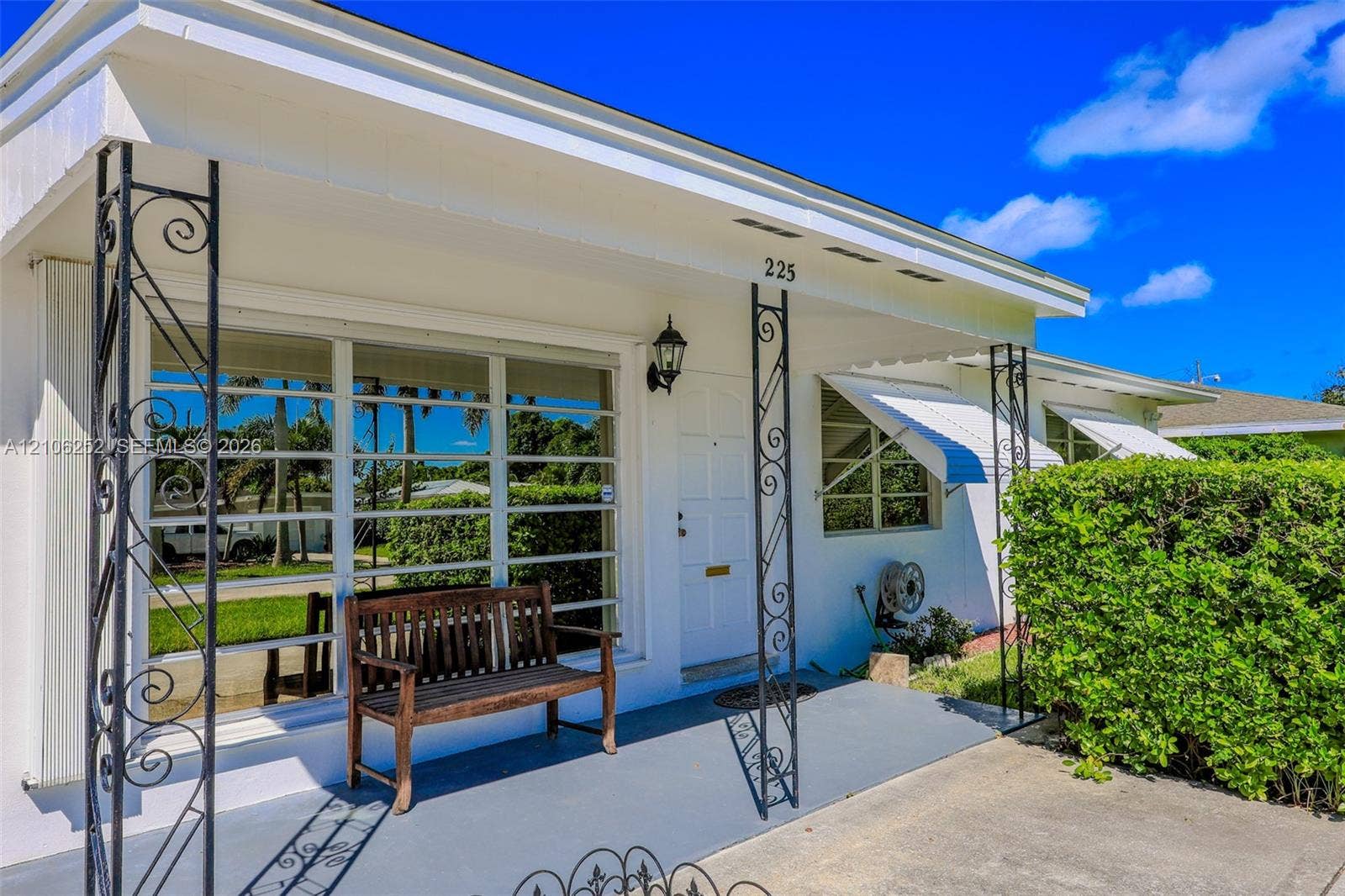 225 E Ilex Drive, Lake Park, Lake Park, FL 33403 Covered front porch featuring decorative wrought iron columns, large picture windows, and metal window awnings