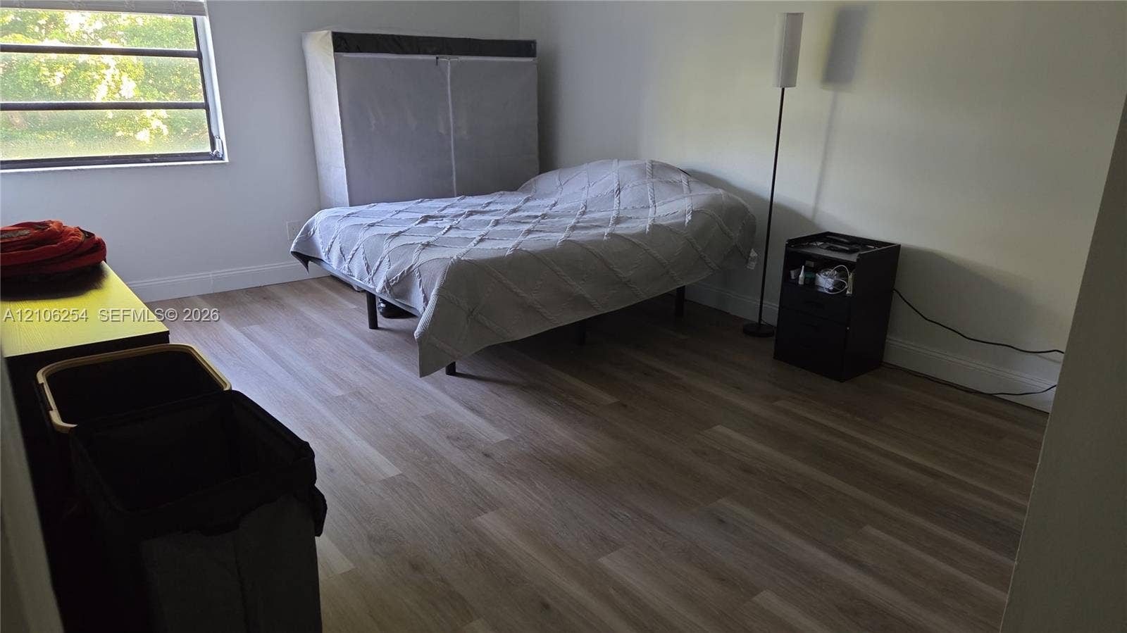 Neutral-toned room featuring wood-finish flooring and a window with a horizontal blind