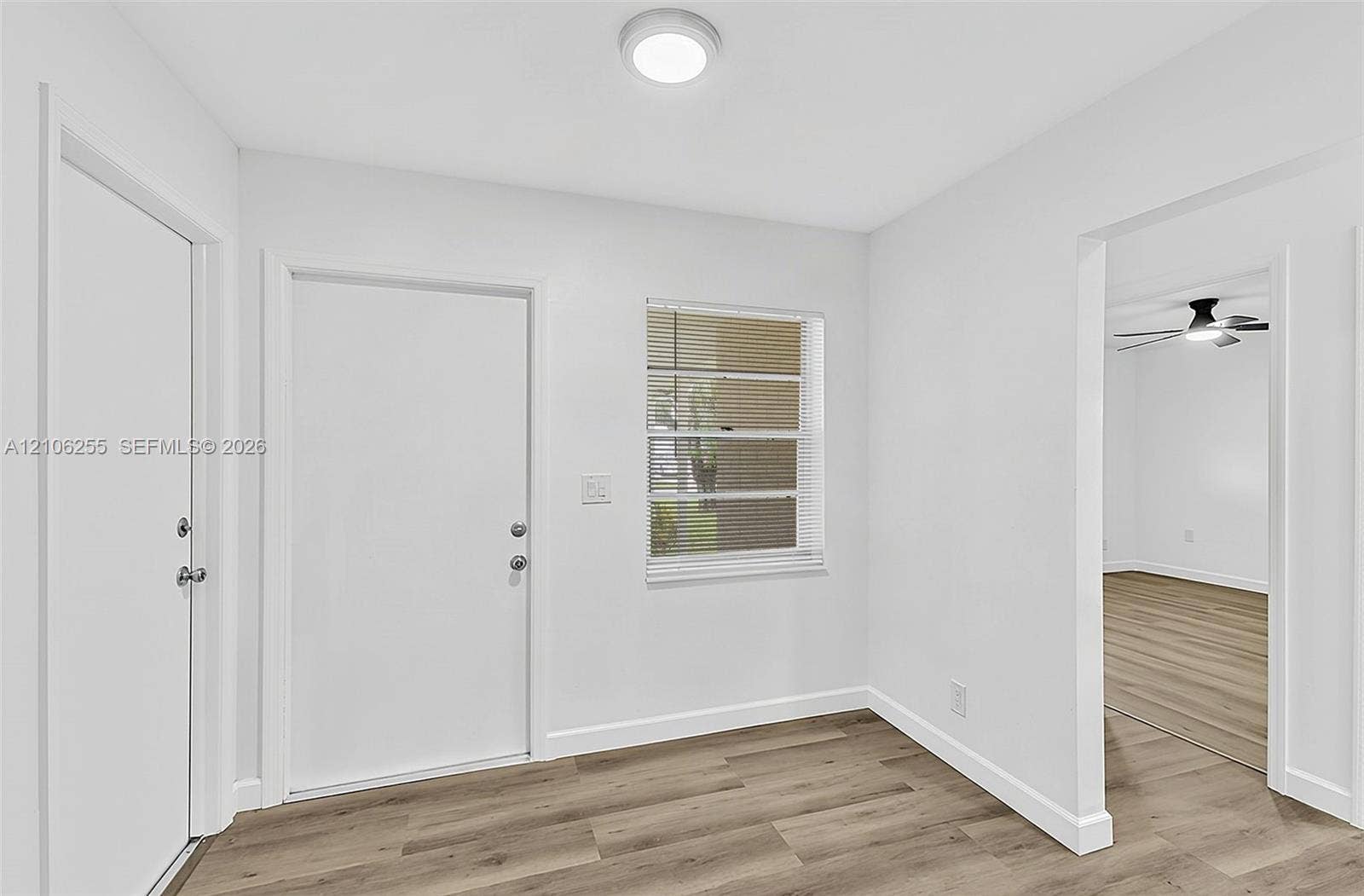6118 Dusenburg Road, Delray Beach, FL 33484 Neutral interior space featuring wood-finish flooring, a flush-mount ceiling light fixture, and horizontal blind window treatments