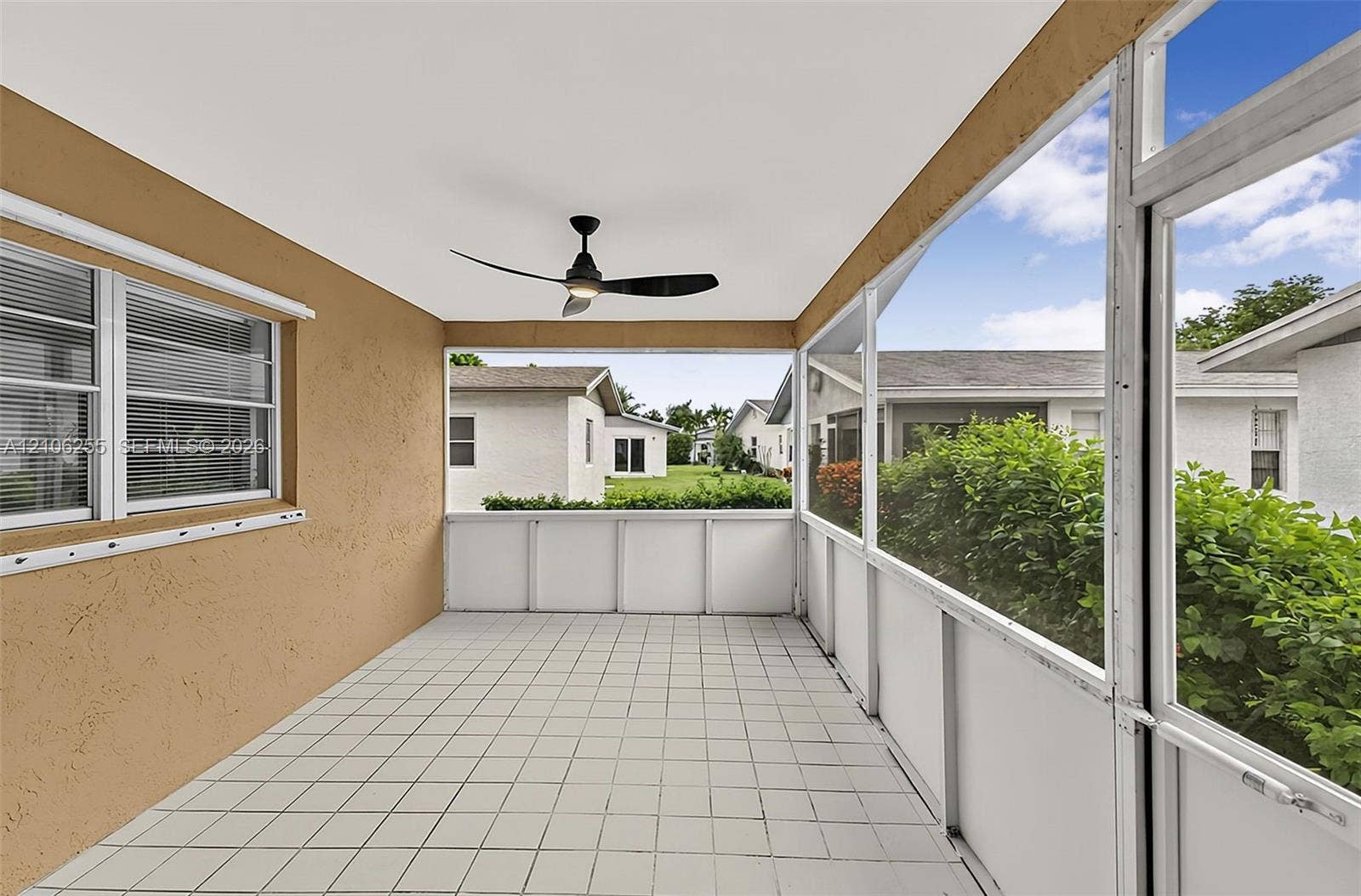 6118 Dusenburg Road, Delray Beach, FL 33484 Screen-enclosed porch featuring white tile flooring, stucco wall finish, and a ceiling-mounted matte black fan
