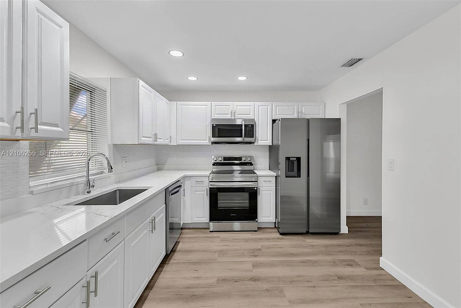 6118 Dusenburg Road, Delray Beach, FL 33484 Kitchen featuring white shaker-style cabinetry, white quartz countertops, stainless steel appliances, and wood-finish flooring