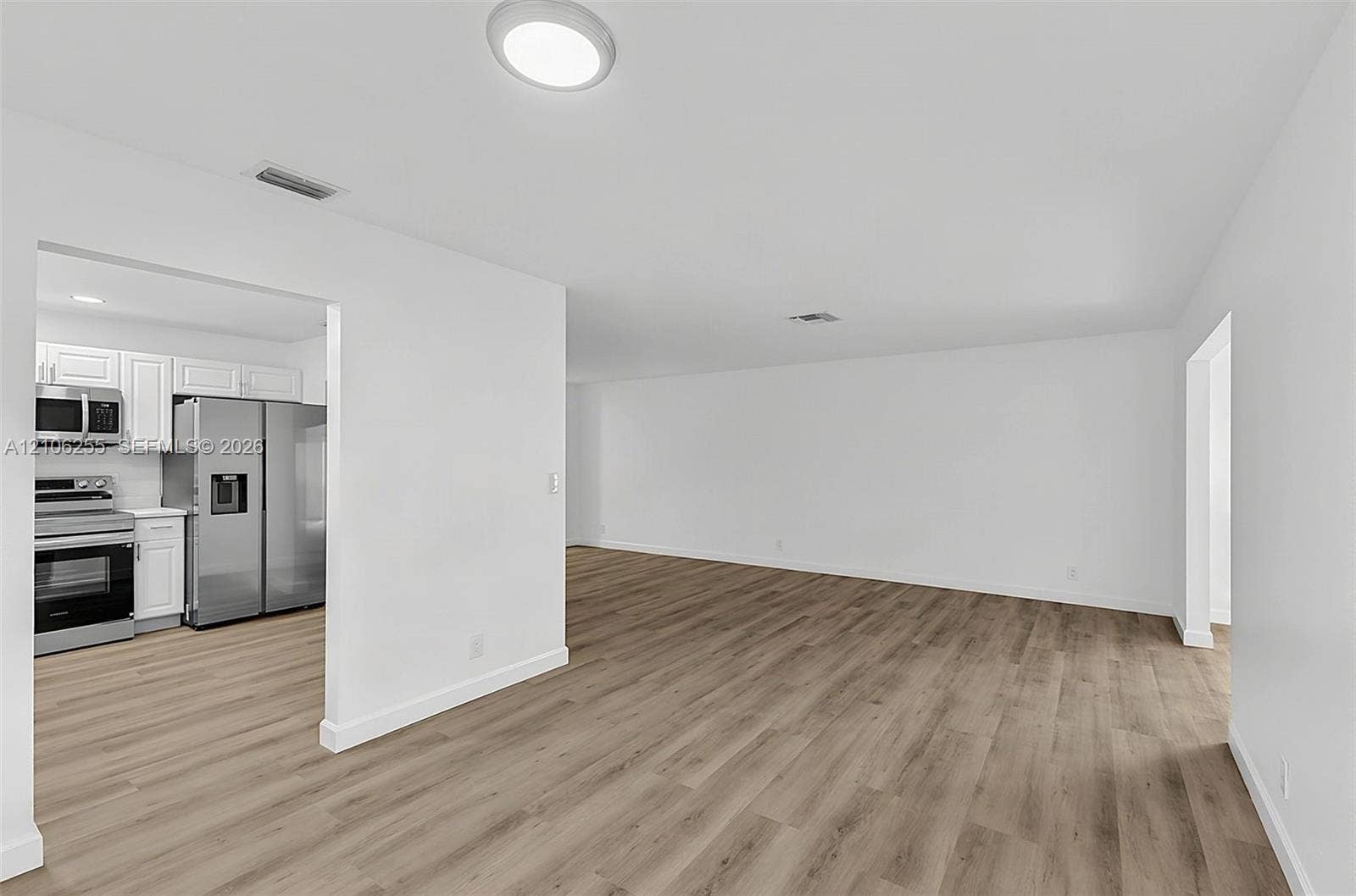 6118 Dusenburg Road, Delray Beach, FL 33484 Open-concept interior featuring wood-finish flooring, recessed lighting, and a kitchen equipped with stainless steel appliances and white cabinetry