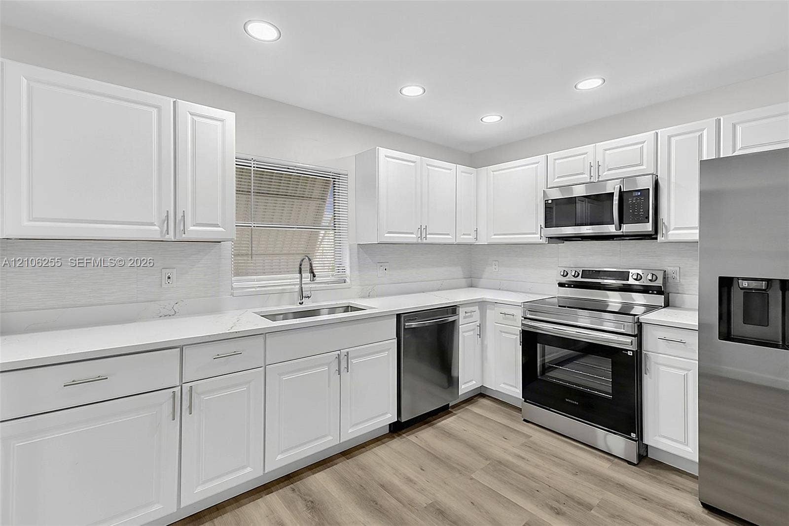 6118 Dusenburg Road, Delray Beach, FL 33484 Kitchen featuring white shaker-style cabinetry, quartz countertops, stainless steel appliances, recessed lighting, and wood-finish flooring