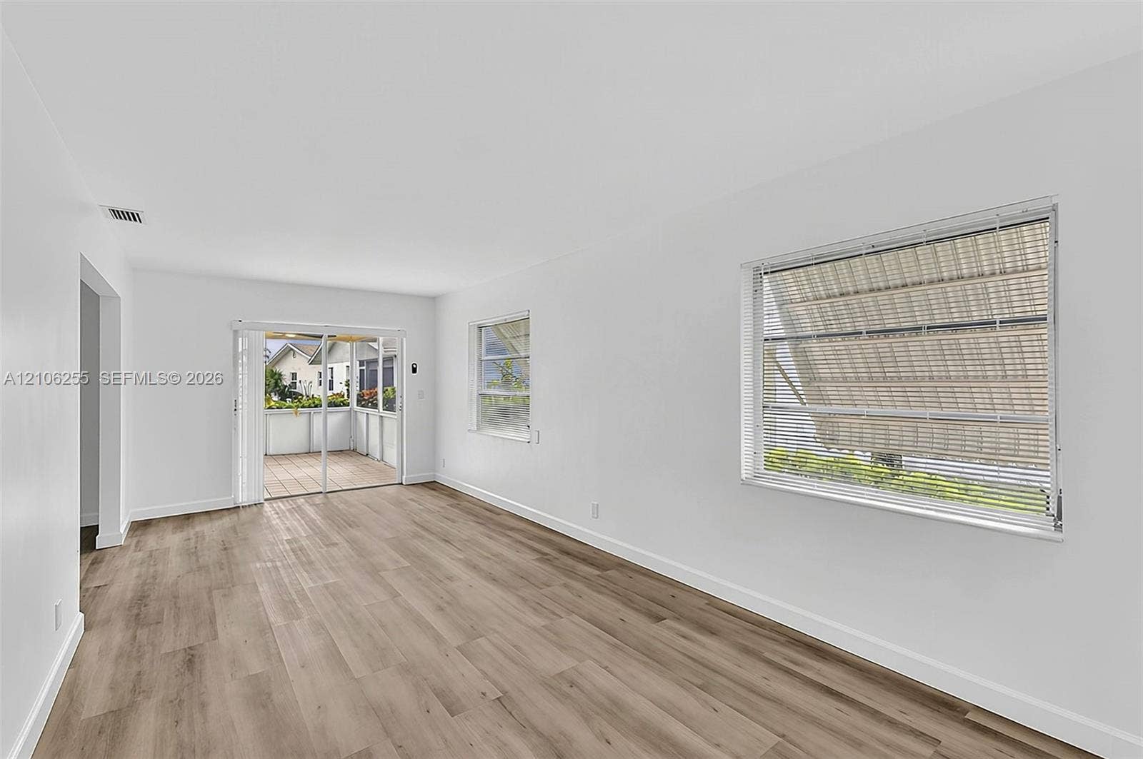 6118 Dusenburg Road, Delray Beach, FL 33484 Neutral interior featuring wood-finish flooring, horizontal window blinds, and sliding glass doors