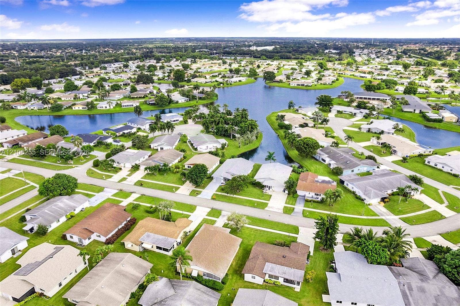 6118 Dusenburg Road, Delray Beach, FL 33484 Aerial perspective of a residential community featuring a central waterway, manicured lawn areas, and mature landscaping