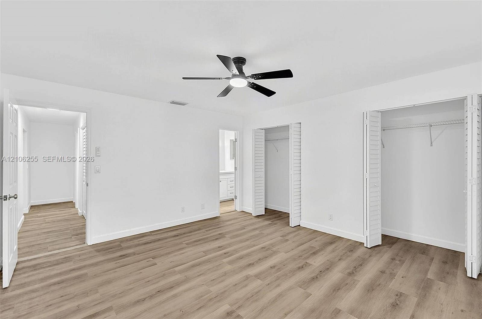 6118 Dusenburg Road, Delray Beach, FL 33484 Room featuring wood-finish flooring, a matte black ceiling fan with an integrated light fixture, and dual closets with bi-fold doors