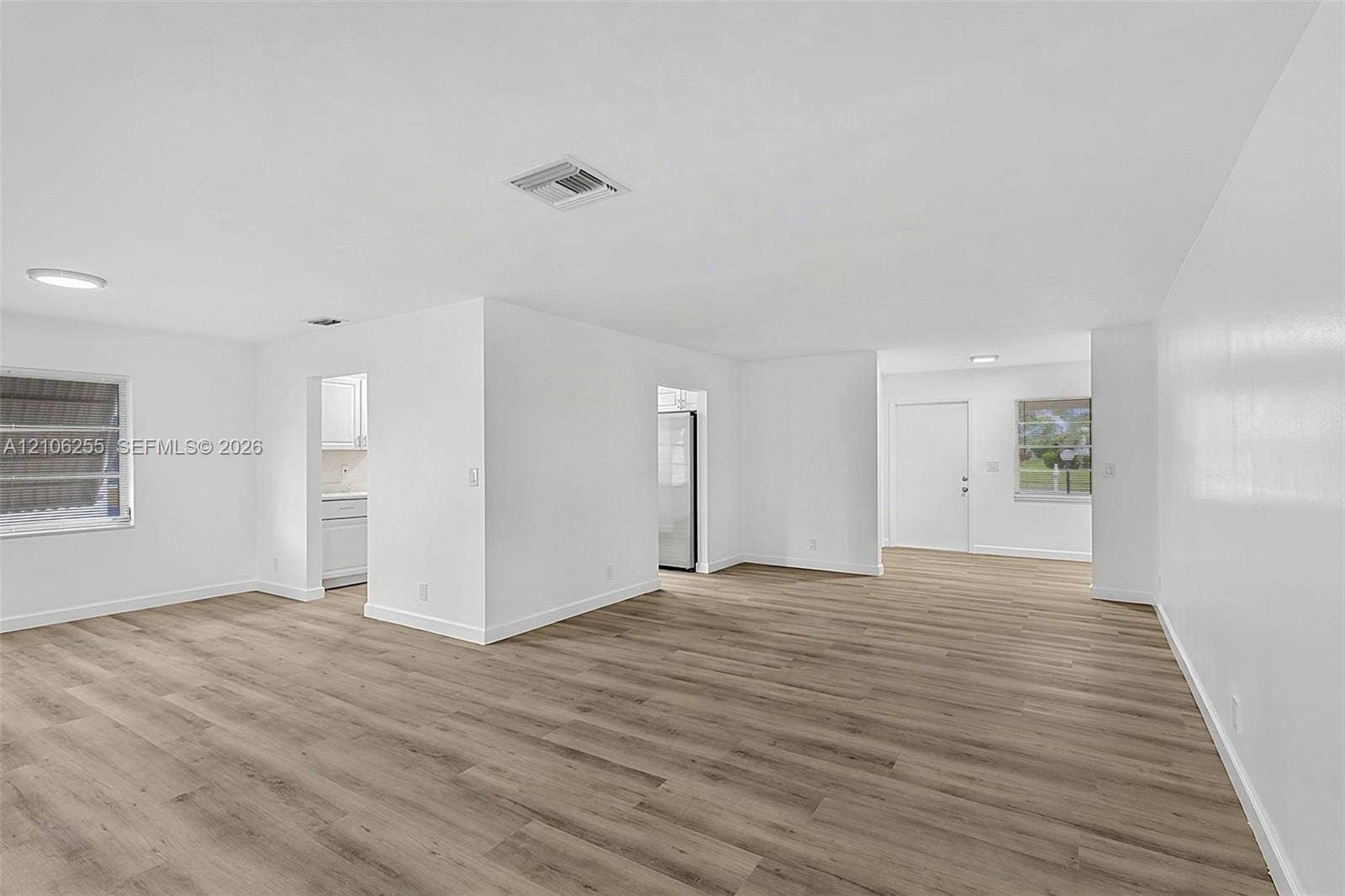 6118 Dusenburg Road, Delray Beach, FL 33484 Open-concept interior featuring wood-finish flooring, crisp white walls, flush-mount lighting, and dual windows