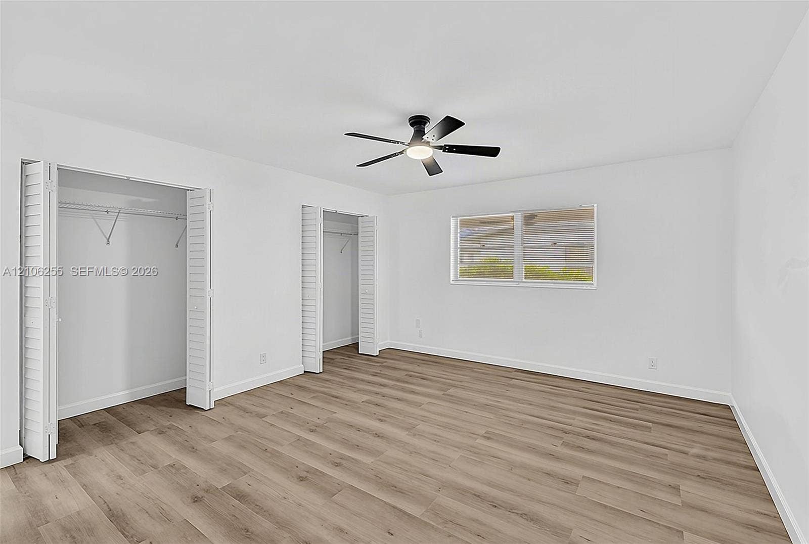 6118 Dusenburg Road, Delray Beach, FL 33484 Neutral-toned wood-finish flooring, two closets with louvered folding doors, and a ceiling-mounted light fixture with fan