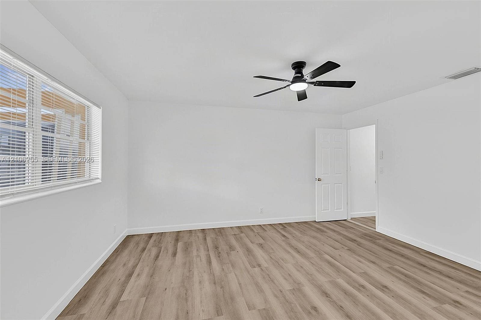 6118 Dusenburg Road, Delray Beach, FL 33484 Neutral interior featuring wood-finish flooring, white walls, a multi-blade ceiling fan with integrated lighting, and a six-panel interior door