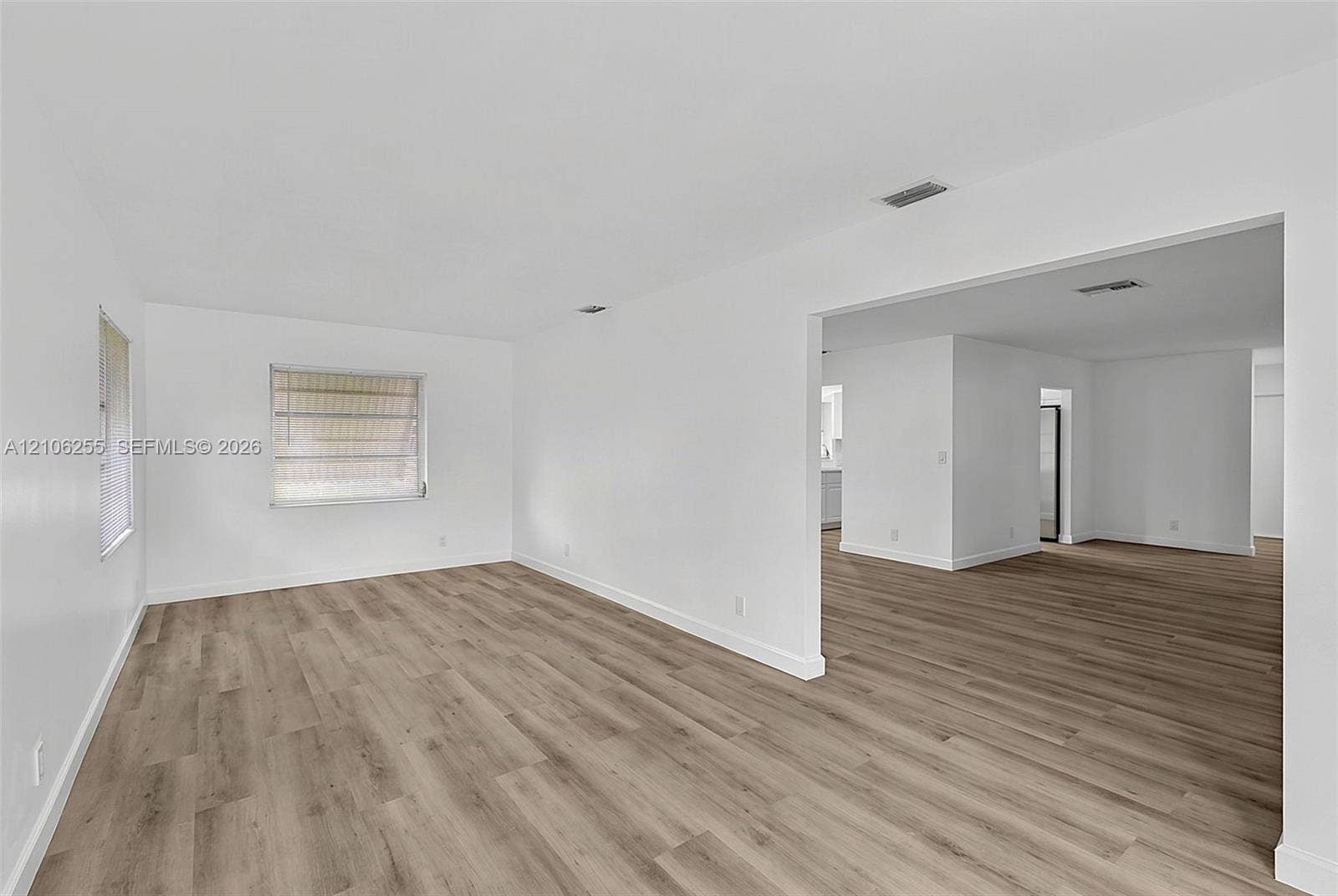 6118 Dusenburg Road, Delray Beach, FL 33484 Interior space featuring light-toned wood-finish flooring, crisp white walls, and multiple windows with louvered shades