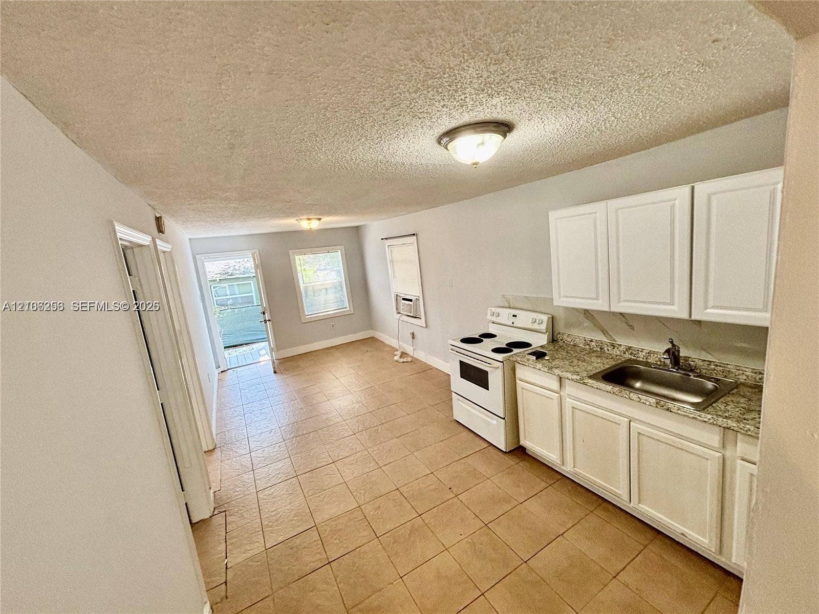 820 21st Street, West Palm Beach, FL 33407 Kitchen featuring white shaker-style cabinetry, stone-patterned countertops, a stainless steel sink, a freestanding electric range, and ceramic tile flooring