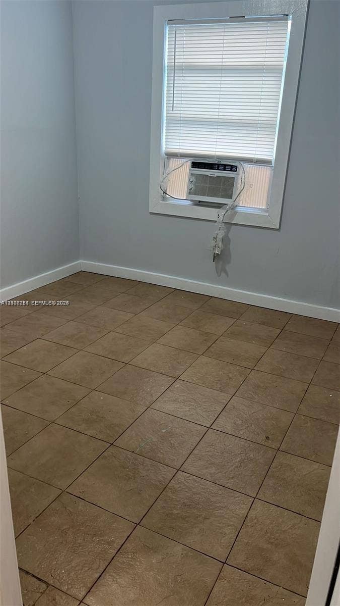 820 21st Street, West Palm Beach, FL 33407 Neutral-toned walls, square ceramic tile flooring, and a single-pane window with installed mini-blinds