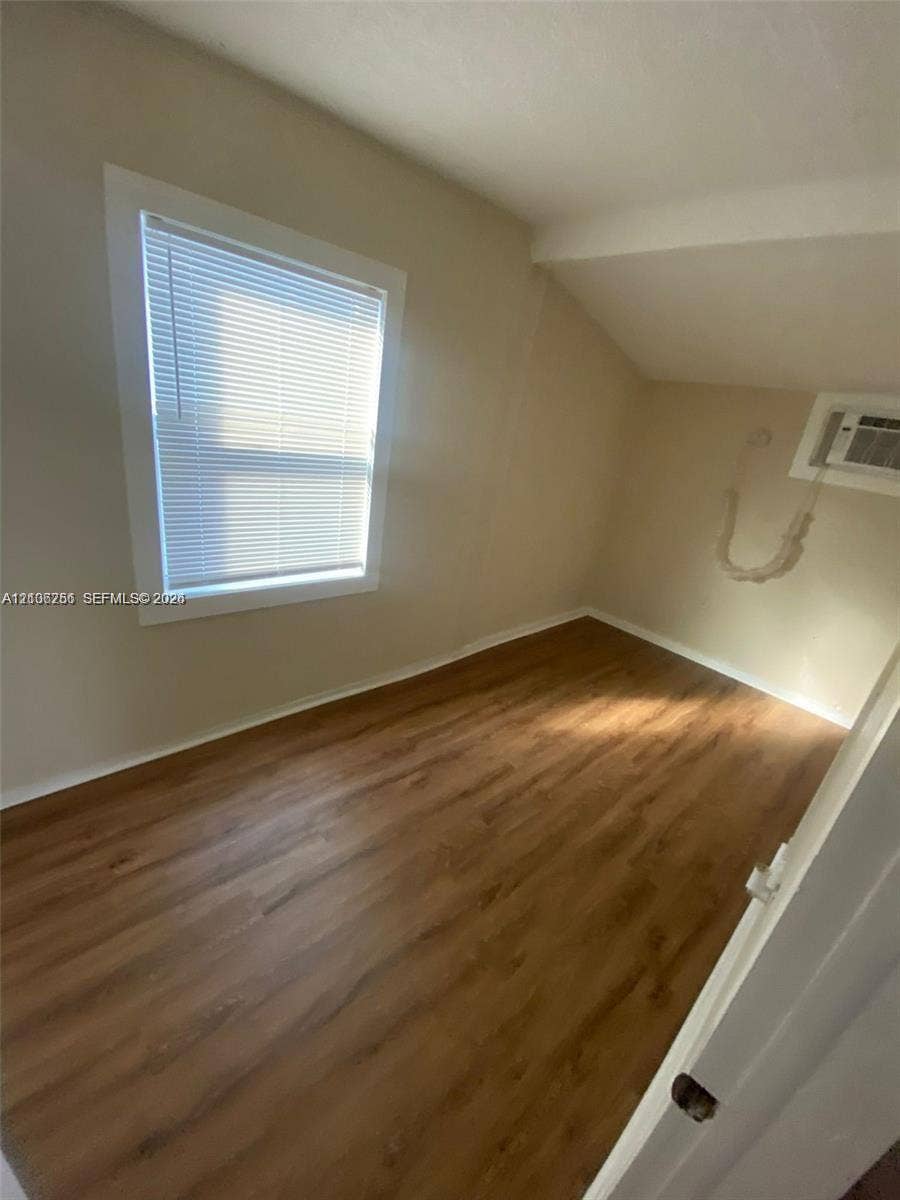 820 21st Street, West Palm Beach, FL 33407 Neutral interior featuring wood-finish flooring, white window trim, and a wall-mounted unit