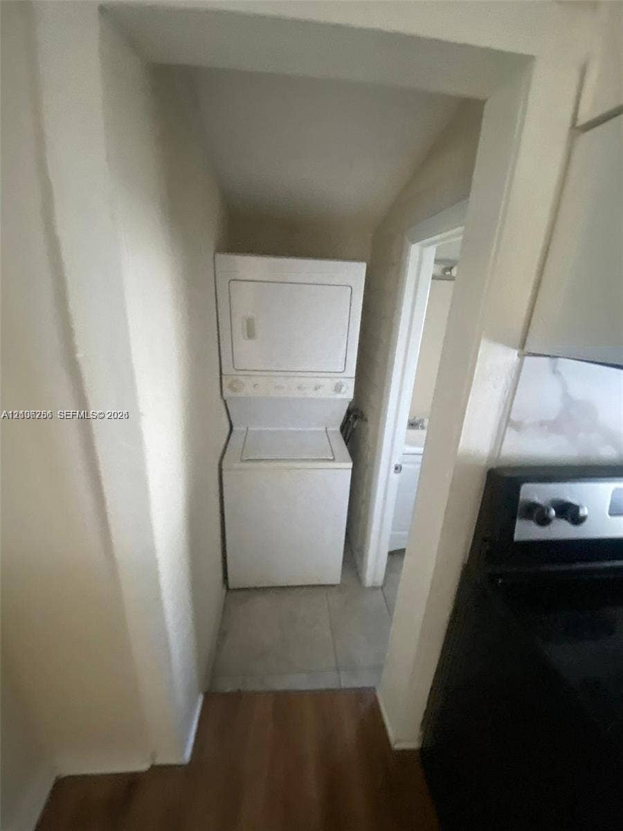 820 21st Street, West Palm Beach, FL 33407 Dedicated laundry nook featuring a white stacked washer and dryer unit, set against light-toned tile flooring