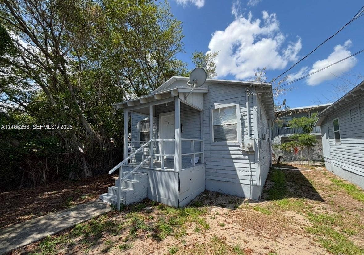 820 21st Street, West Palm Beach, FL 33407 Exterior featuring light blue lap siding, a covered front porch with simple railing, and concrete steps