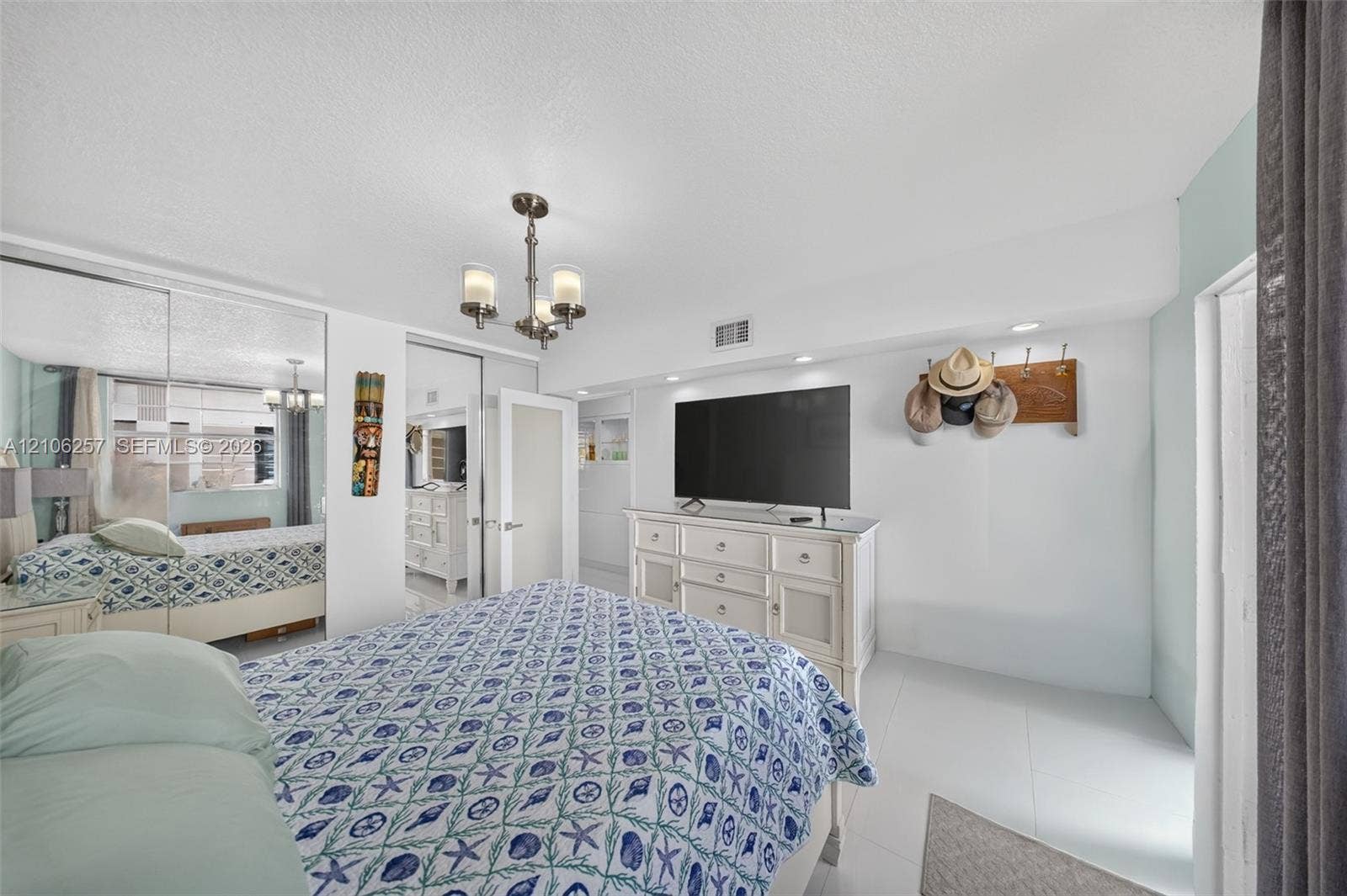 Room featuring polished tile flooring, full-wall mirrored closet doors, a multi-arm chandelier, and recessed ceiling lighting