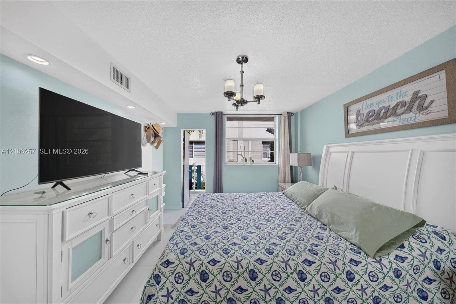 Bedroom featuring recessed accent lighting, a multi-light metal chandelier, and a built-in architectural soffit. Rear balcony off the bedroom.