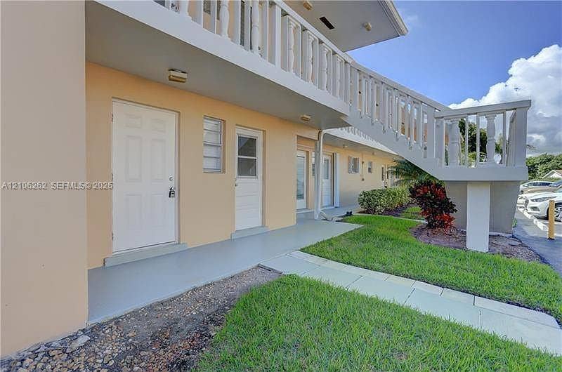 2212 NE 1st Way, #101, Boynton Beach, FL 33435 Exterior facade featuring a concrete walkway, elevated stairs with decorative balustrade railings, and integrated surface-mounted lighting