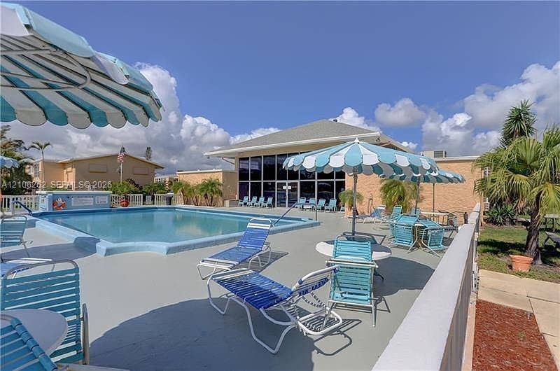 2212 NE 1st Way, #101, Boynton Beach, FL 33435 Swimming pool with concrete decking, surrounded by building exterior with glass facade