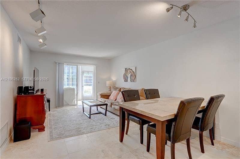 2212 NE 1st Way, #101, Boynton Beach, FL 33435 Open-concept room featuring light-toned tile flooring, adjustable multi-head track lighting, and a sliding glass door providing external access
