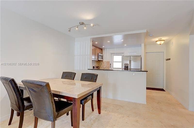 2212 NE 1st Way, #101, Boynton Beach, FL 33435 Kitchen featuring a pass-through counter, stainless steel appliances, wood cabinetry, and recessed lighting, finished with stone-tile flooring