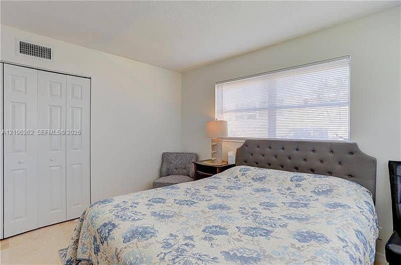 2212 NE 1st Way, #101, Boynton Beach, FL 33435 Room featuring neutral wall paint, a large horizontal window with fitted blinds, and a built-in closet with paneled double doors
