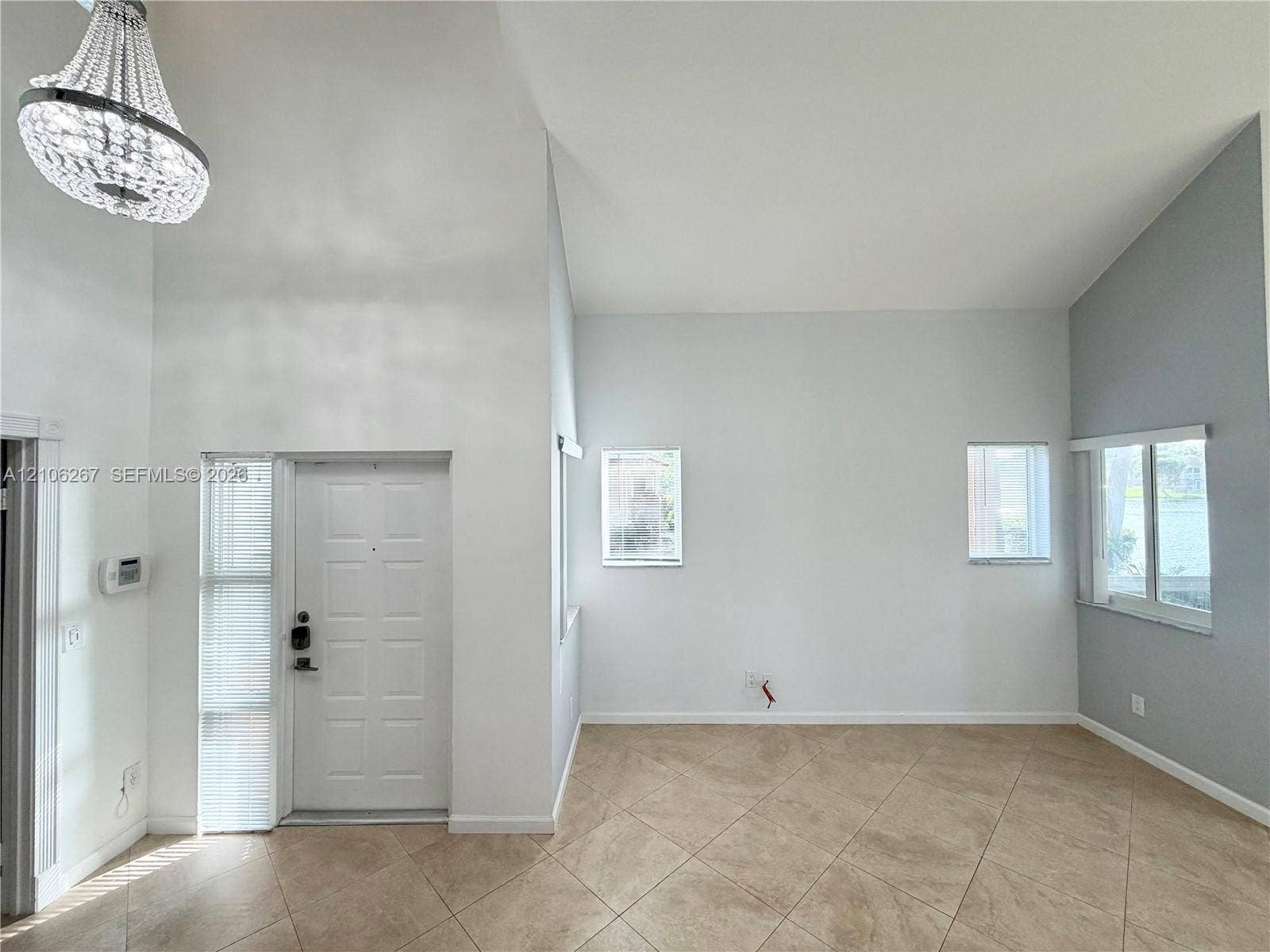 Neutral-toned interior space featuring wall-to-wall carpeting, a sliding louvered closet door, and a single window with white trim