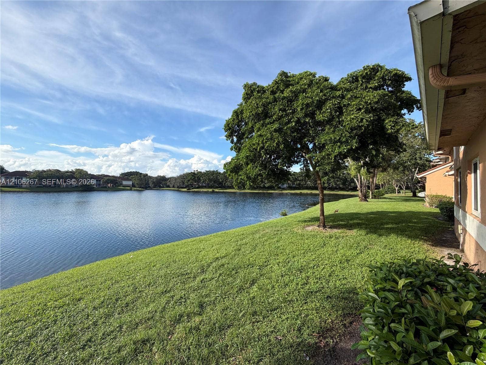 Waterfront parcel featuring a manicured lawn, mature trees, and landscaping