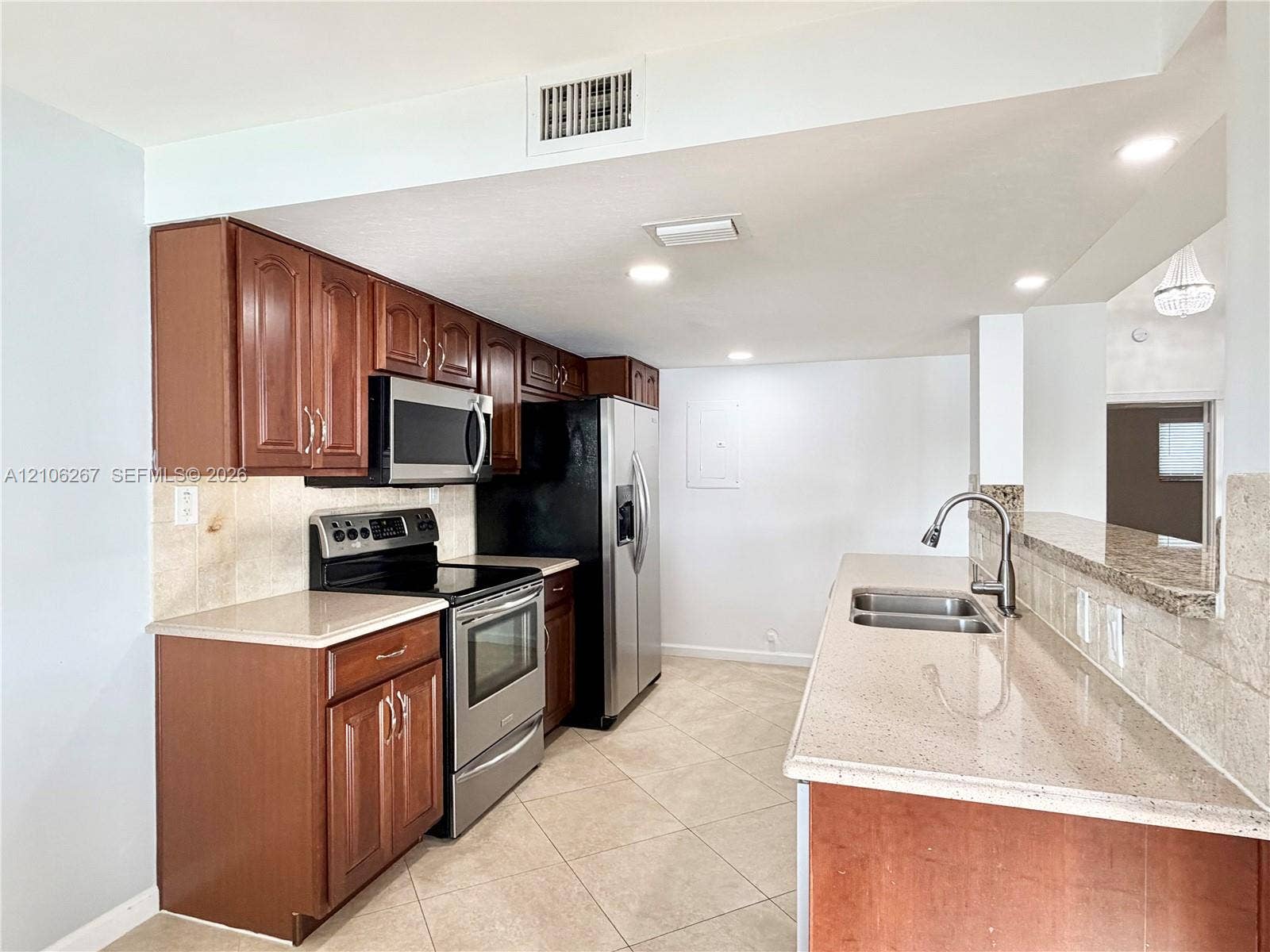 Kitchen featuring wood cabinetry, stone-finish countertops, stainless steel appliances, a double-basin undermount sink, and recessed lighting