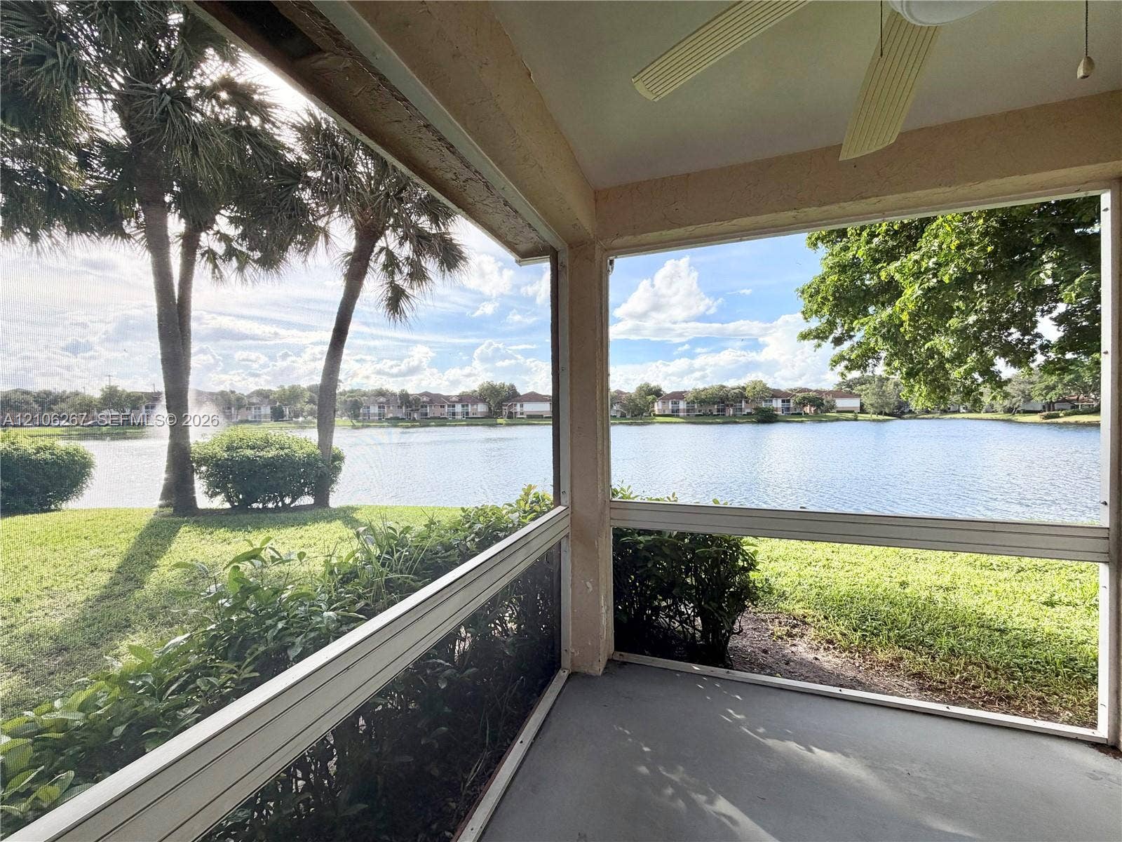 Screened-in patio featuring a ceiling fan with integrated lighting, concrete flooring, and water frontage