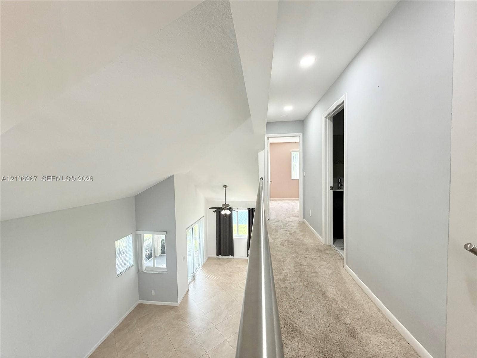 Open mezzanine featuring a metal railing, neutral carpeting, recessed ceiling lighting, and vaulted ceilings