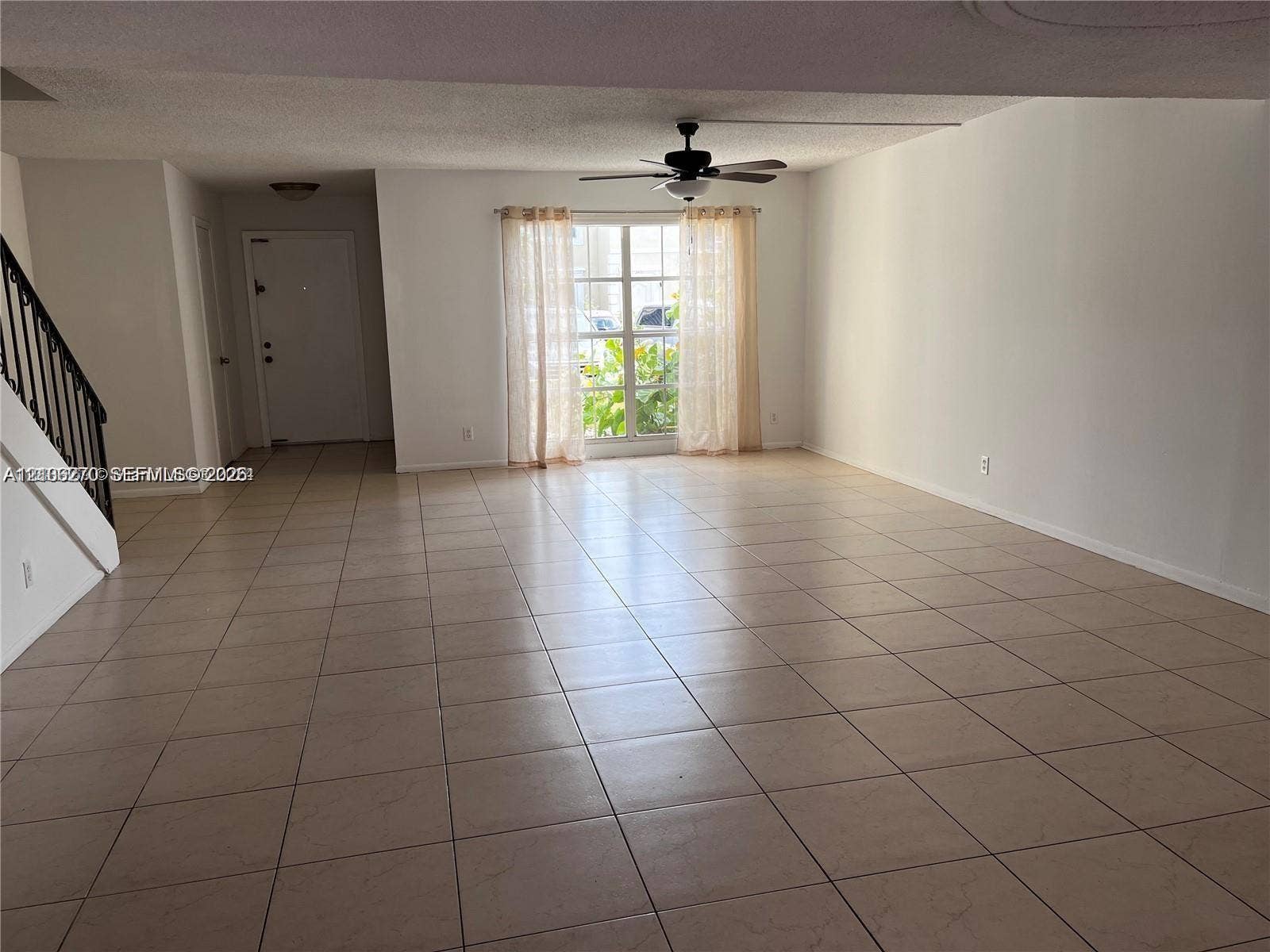 2410 NE 10th Street, #123, Hallandale Beach, Hallandale Beach, FL 33009 Open-concept interior featuring large-format tile flooring, a ceiling fan with integrated lighting, and a staircase with a black metal railing