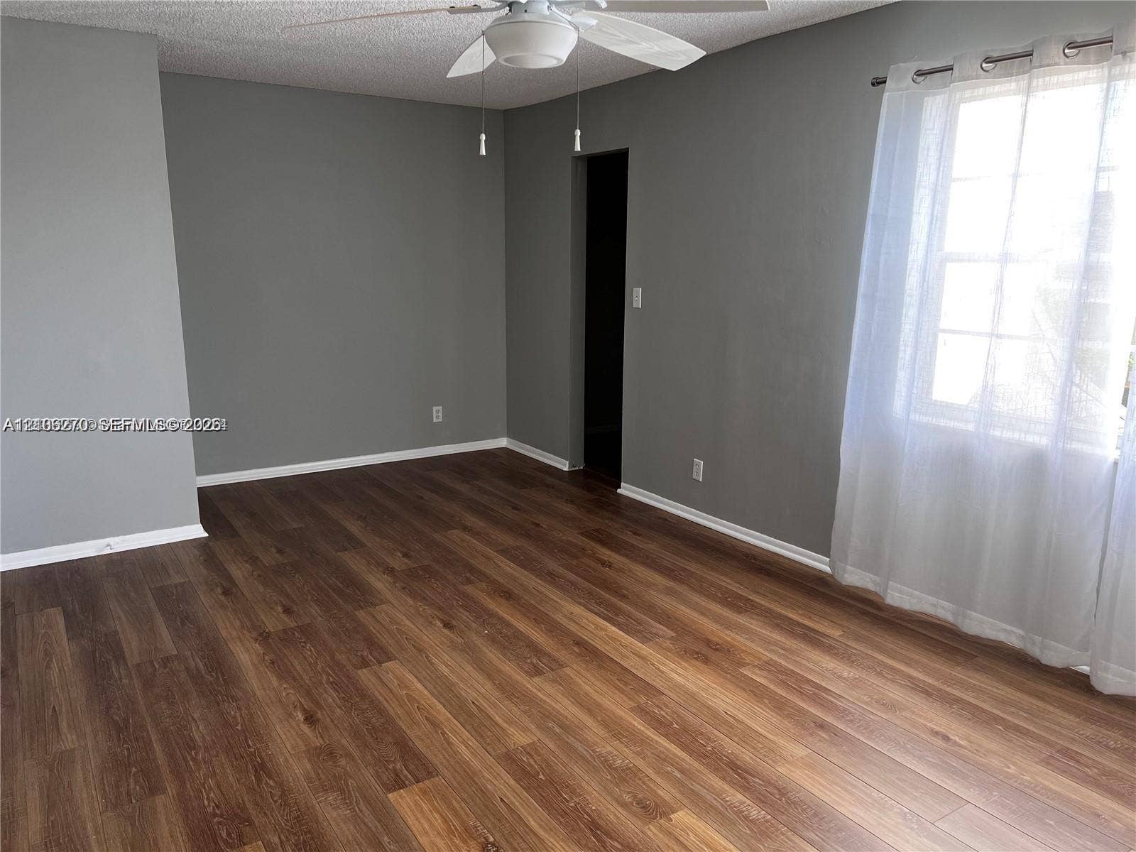 2410 NE 10th Street, #123, Hallandale Beach, Hallandale Beach, FL 33009 Room featuring wood-finish flooring, neutral-toned walls, and a ceiling fan with integrated lighting