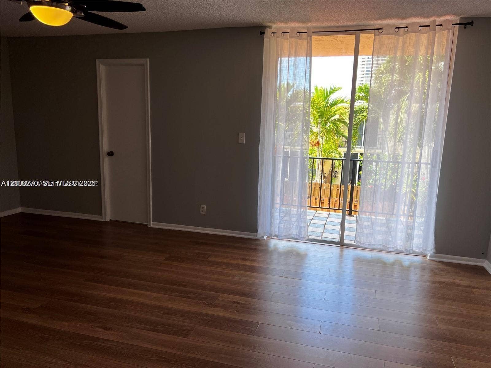 2410 NE 10th Street, #123, Hallandale Beach, Hallandale Beach, FL 33009 Wood-finish flooring, sliding glass balcony door, metal balcony railing, and ceiling-mounted fan with integrated lighting