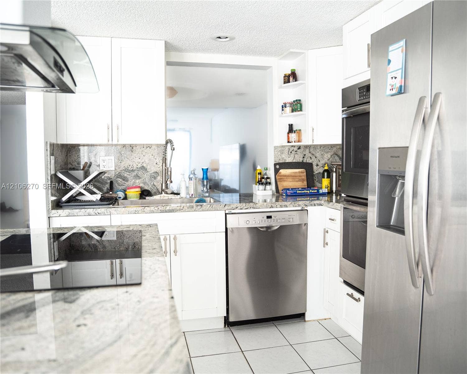 2410 NE 10th Street, #123, Hallandale Beach, Hallandale Beach, FL 33009 Kitchen featuring white cabinetry, stone countertops, integrated stainless steel appliances, open shelving, and tile flooring