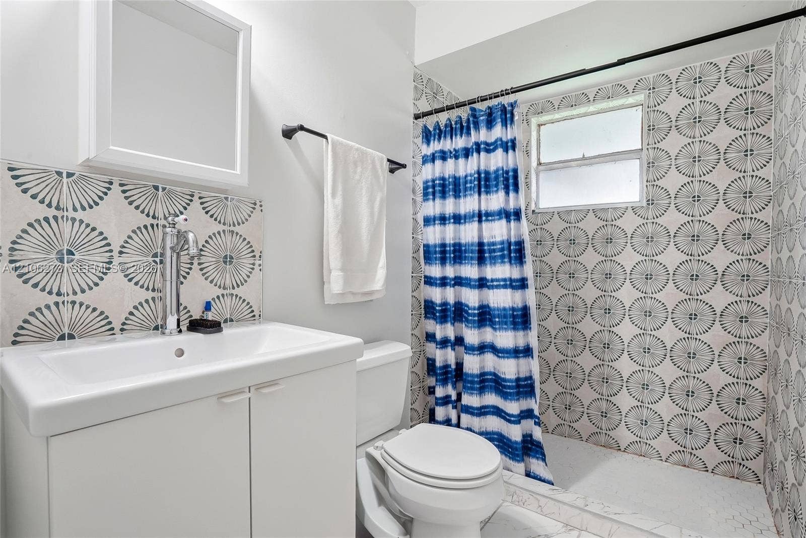 5310 Seagrape Drive, Fort Pierce, FL 34982 Bathroom featuring a white cabinet vanity with an integrated sink, patterned tile backsplash, shower enclosure with patterned tile surround, and a window