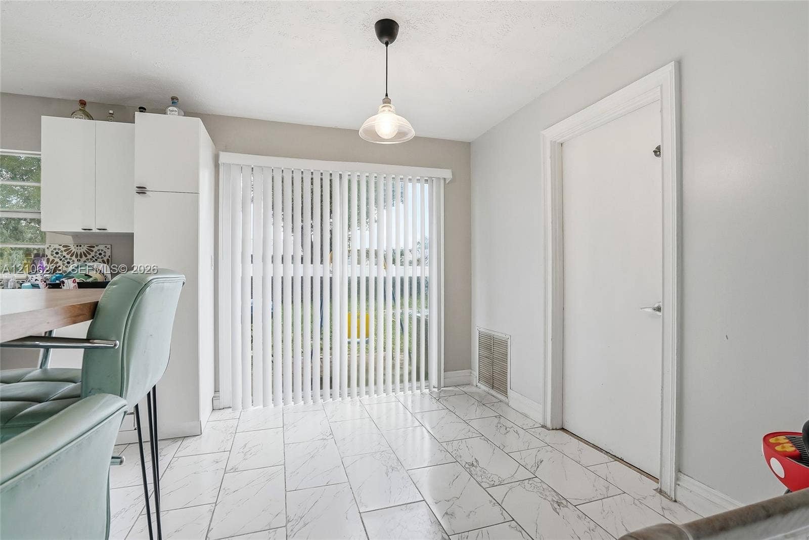 5310 Seagrape Drive, Fort Pierce, FL 34982 Interior space featuring large-format tile flooring with a neutral veined pattern, floor-to-ceiling sliding glass doors, white cabinetry, and a single pendant light fixture