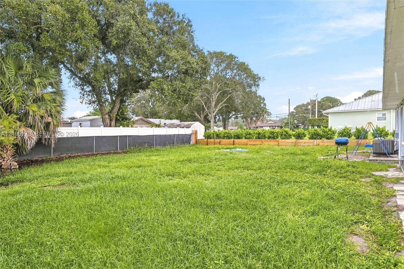 5310 Seagrape Drive, Fort Pierce, FL 34982 Expansive backyard featuring a sprawling lawn, white vinyl perimeter fencing, and mature trees