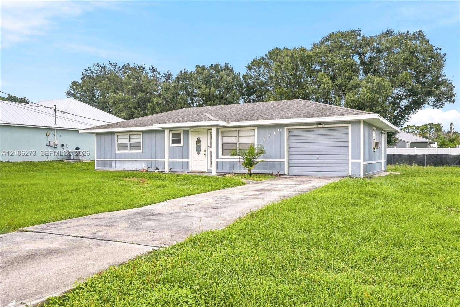 5310 Seagrape Drive, Fort Pierce, FL 34982 Single-story residence featuring light blue vertical siding, a hipped roof, an attached one-car garage, and a concrete driveway