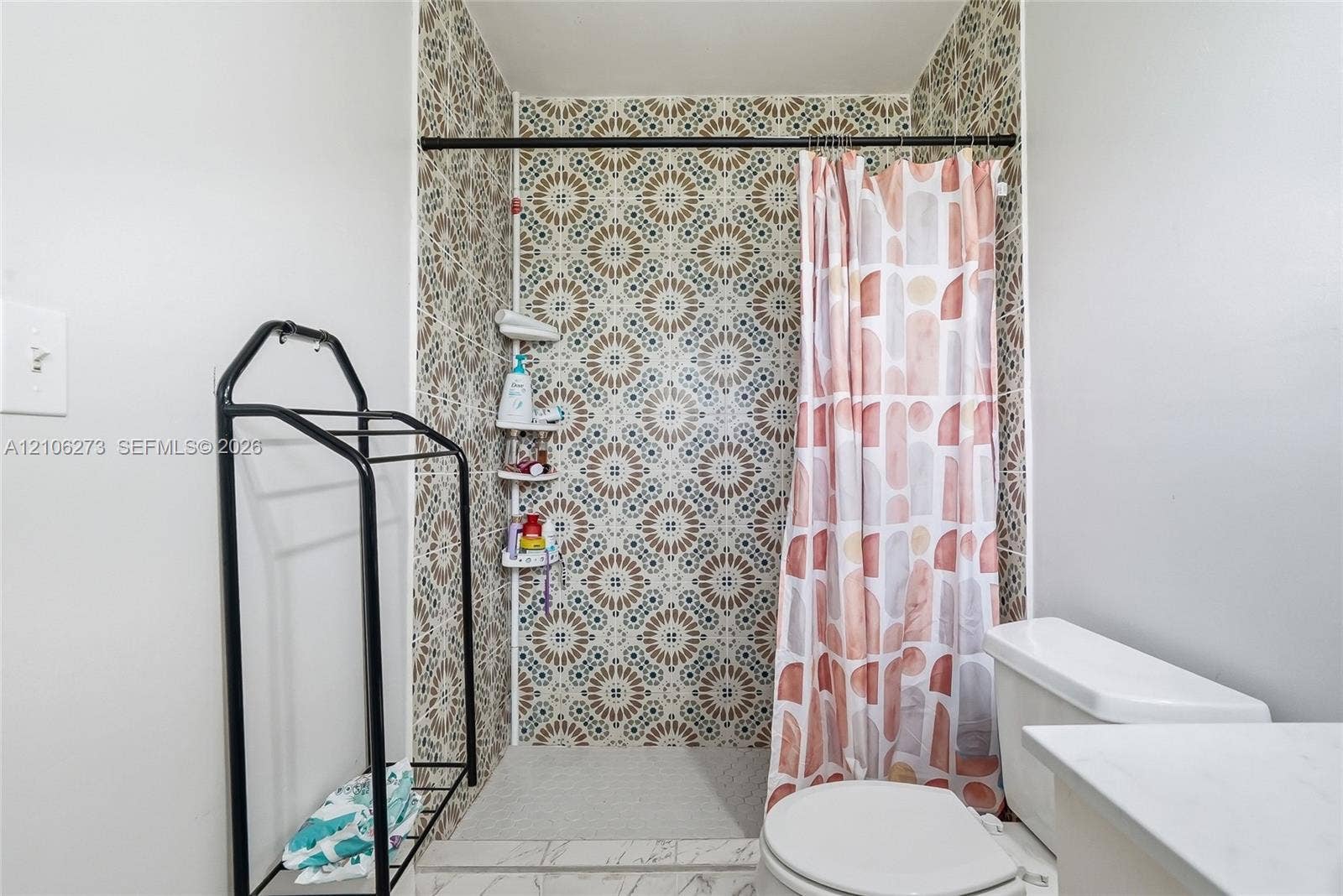 5310 Seagrape Drive, Fort Pierce, FL 34982 Walk-in shower featuring patterned tile walls, built-in shelving, and a matte black shower curtain rod